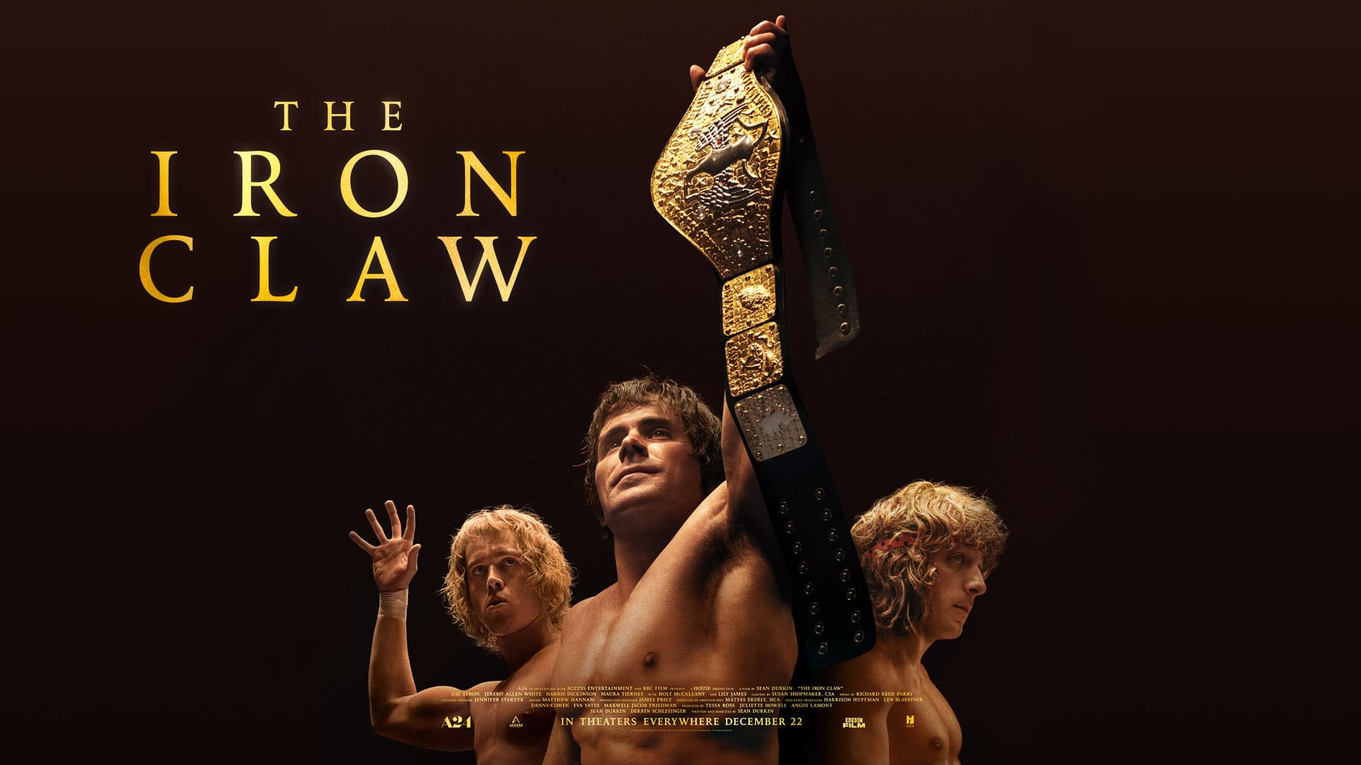 The Iron Claw prop and costume auction event graphic from the A24 film featuring Zac Efron, Lily James, and cast in wrestling attire.